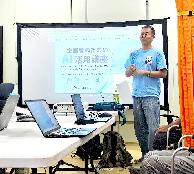 宇城市戸馳島の会場で、生産者のためのAI活用講座のスライドを映しながら話す講師と、机に並んだ参加者のパソコン